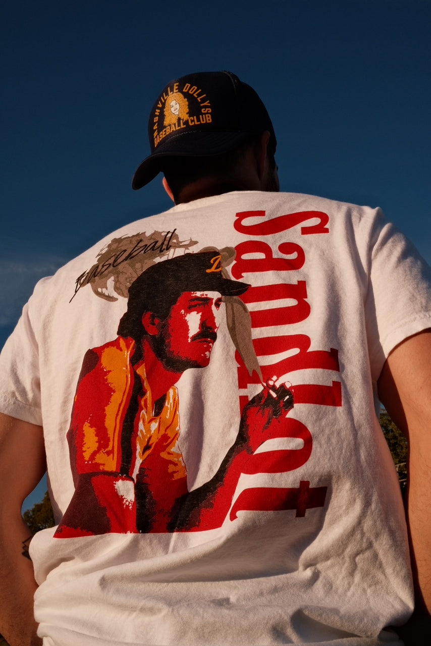Model wearing Sandlot Tee outdoors, showing back graphic of a baseball player and red 'Sandlot' text.