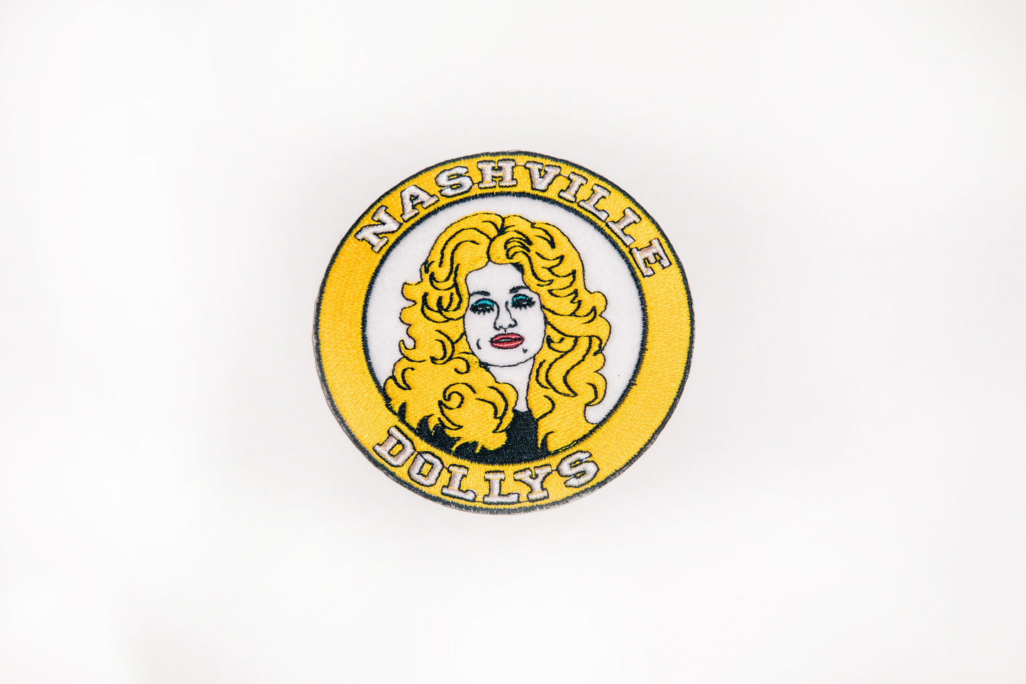 Dolly Parton-inspired patch with Nashville Dollys logo and vibrant yellow borde.