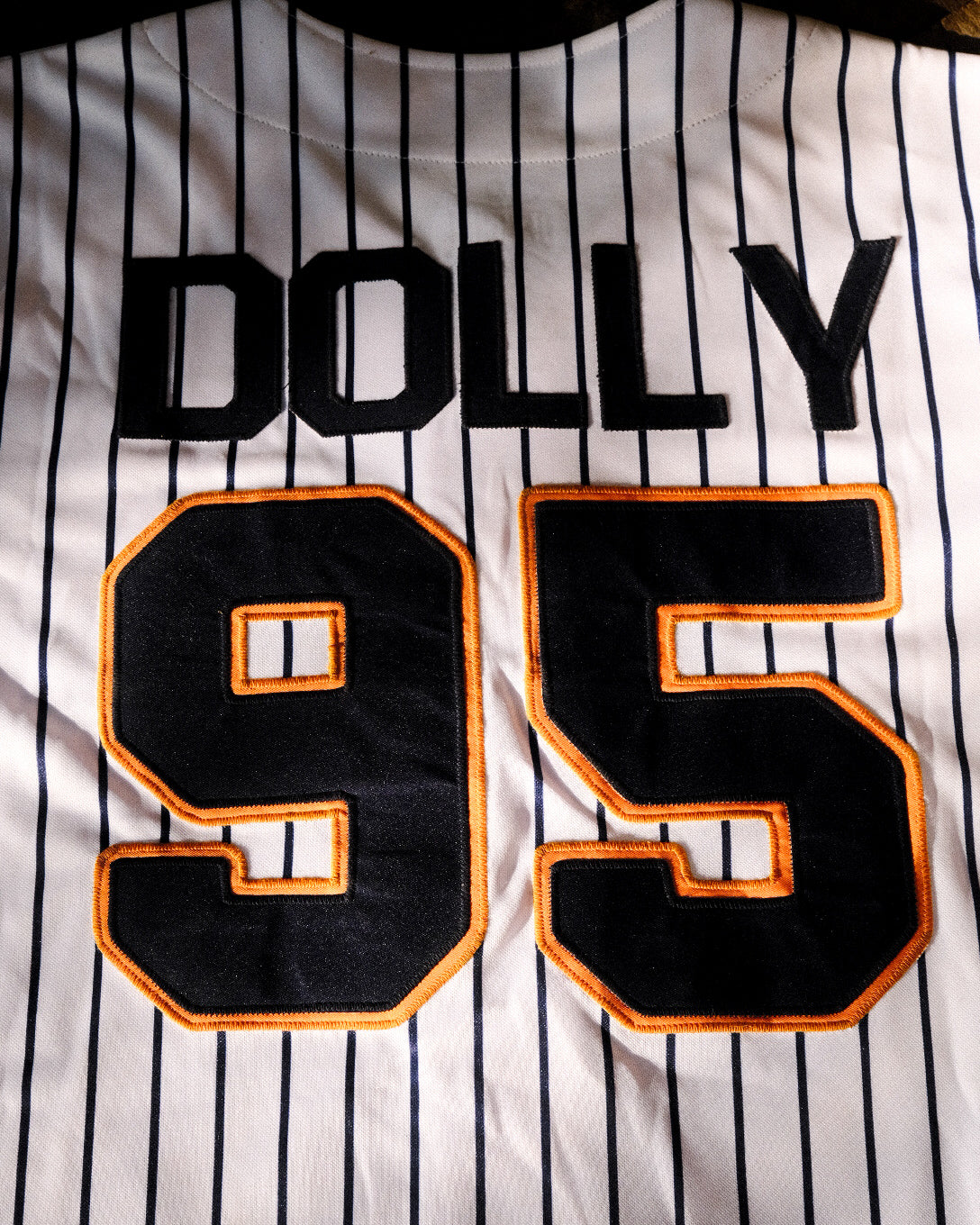 Back of jersey laid flat with 'Dolly' and #95, embroidered in black and orange.