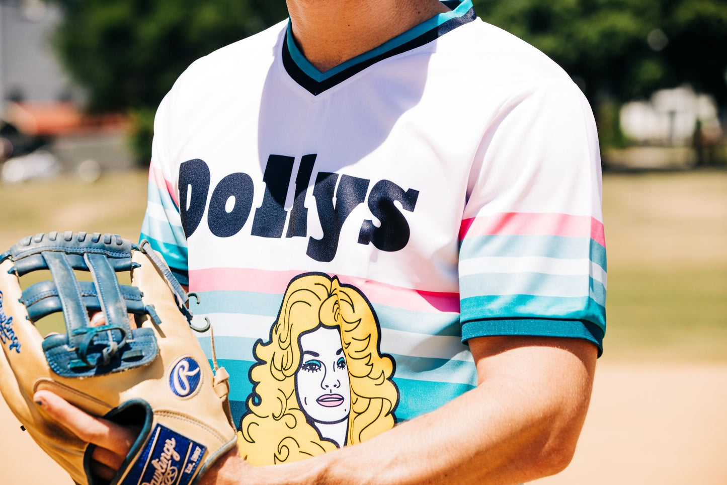 Close-up of Retro 'Sunset' Jersey with Dolly Parton logo, person holding a baseball glove.